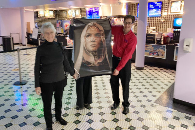 Judith Brown, at left, holds a poster advertising the film, Benedetta.