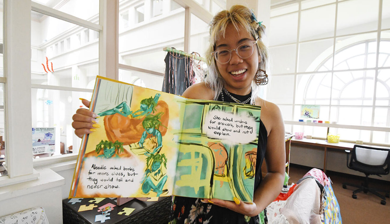 Elim Lee ’22 shows one of the spreads in her children’s book. “On this page, it shows Needle looking out the window of a bus, and I love looking out windows. I feel like every part of this book encapsulates a feeling I’ve felt so deeply about for so long. I wouldn’t have access to show [these feelings] it if wasn’t for this project,” she said.”