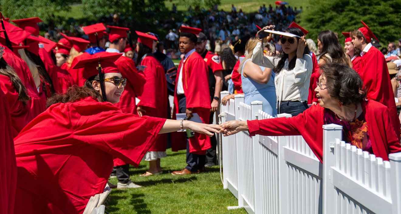 A student and relative reach out to one another at Wesleyan’s 191st Commencement. (Mike Mavredakis)