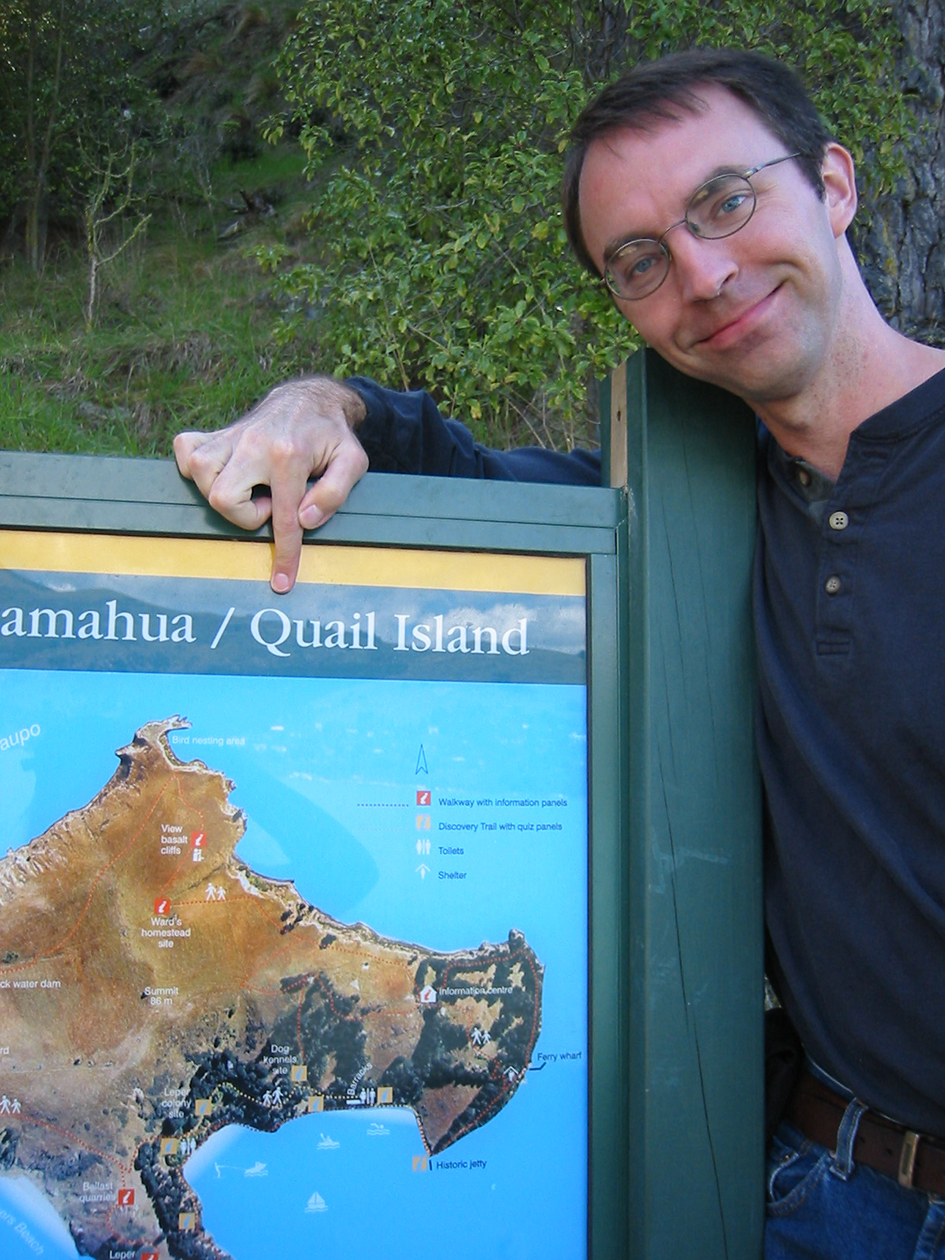Josh Calder next to a map of Quail Island.