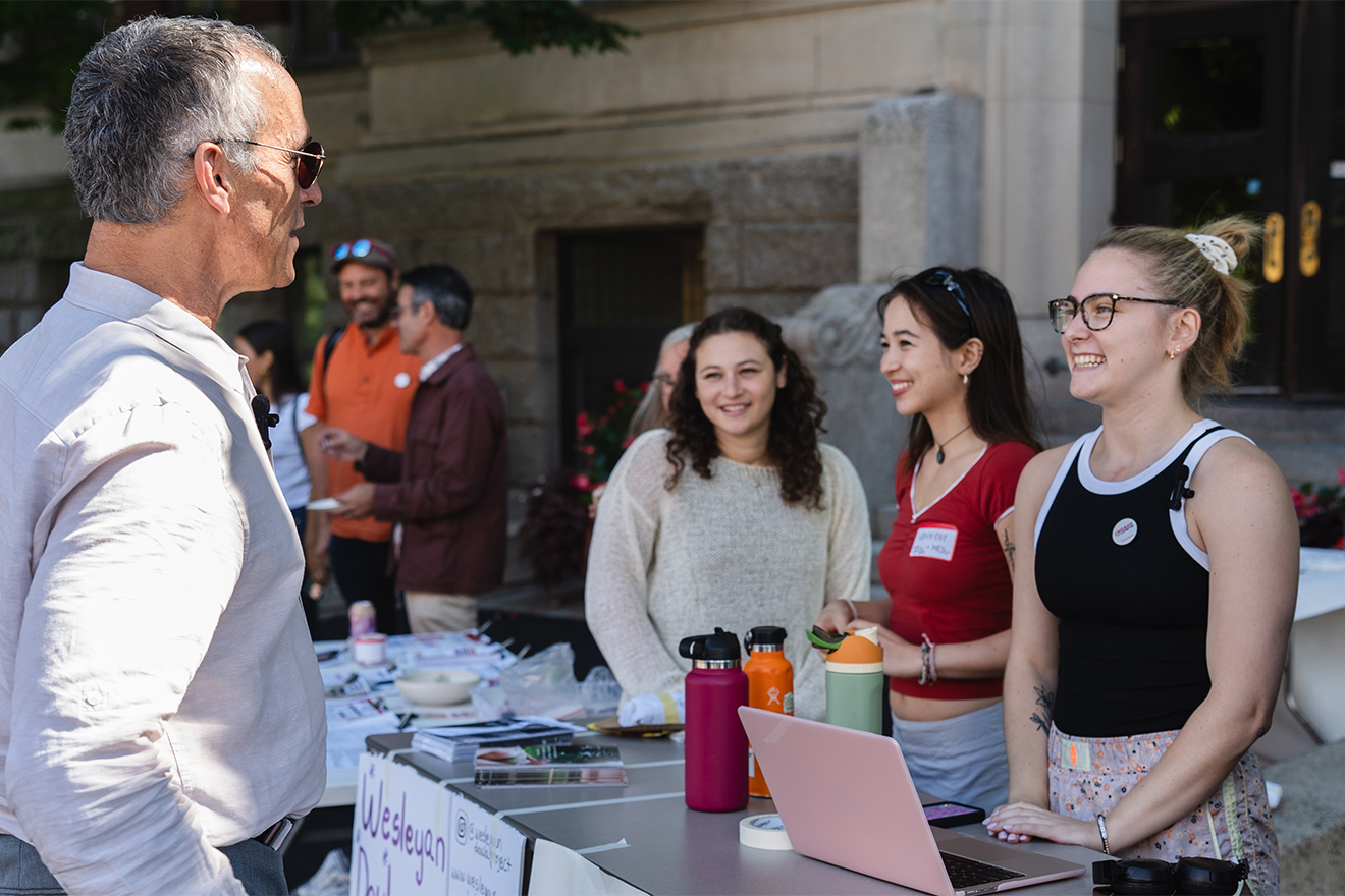 President Roth talking to three students tabling