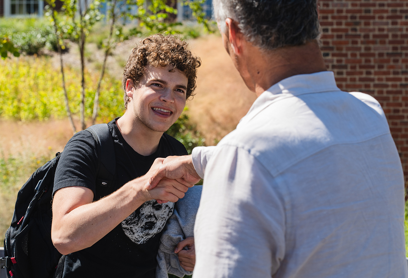President Roth greeting a male student on campus