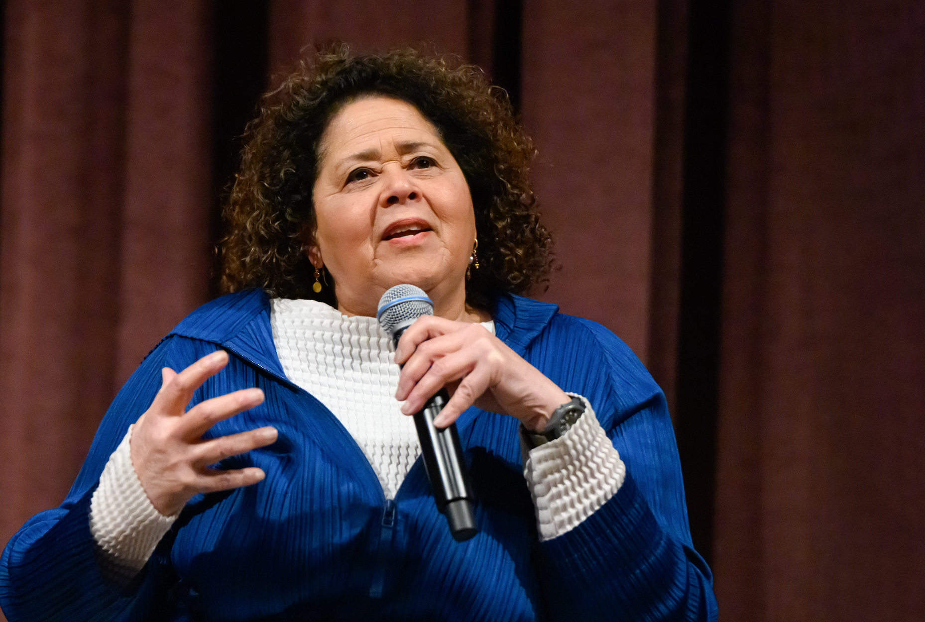 Woman speaking on stage with microphone in hand 