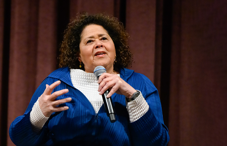 Woman speaking on stage with microphone in hand 