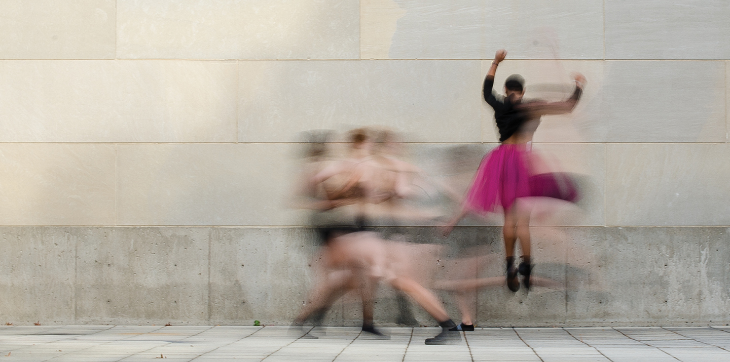 Dancers jumping and moving with motion blur in front of limestone wall