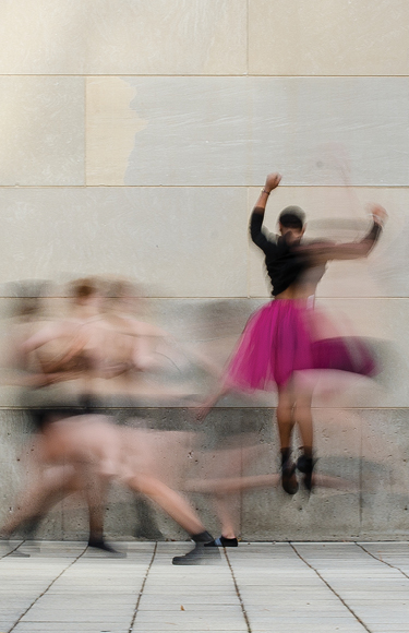 Dancers jumping and moving with motion blur in front of limestone wall - mobile version