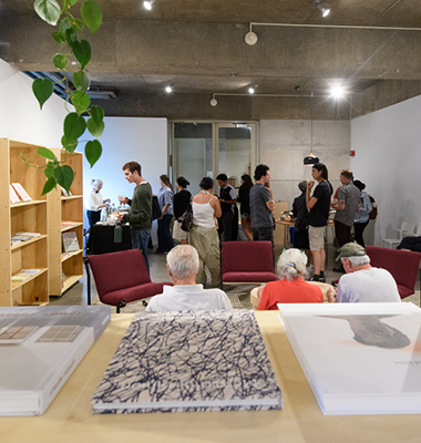 Interior of reading room with books displayed on shelves and people attending reception