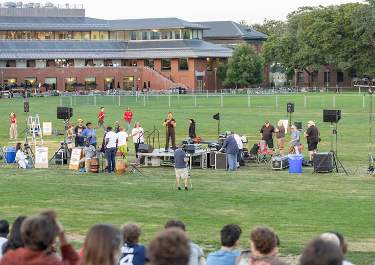 People on and near stage in field in front of audience 