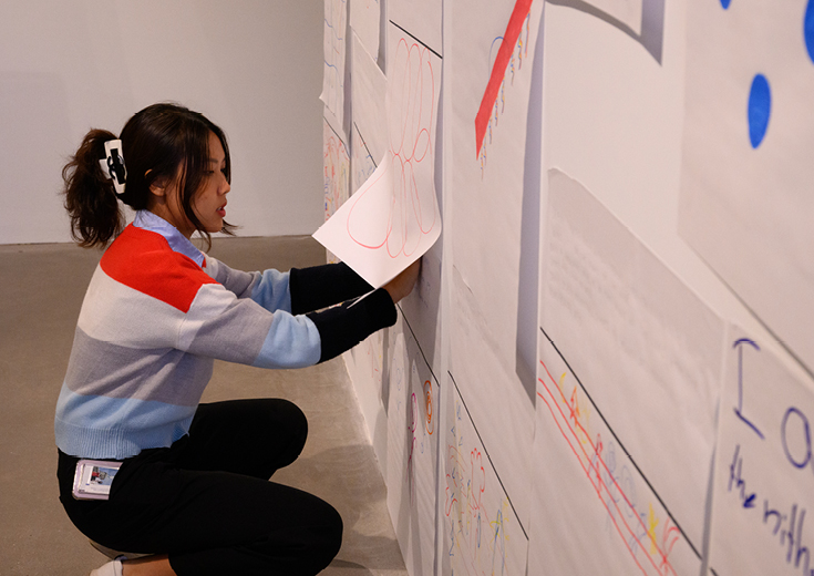 Student putting artwork on gallery wall
