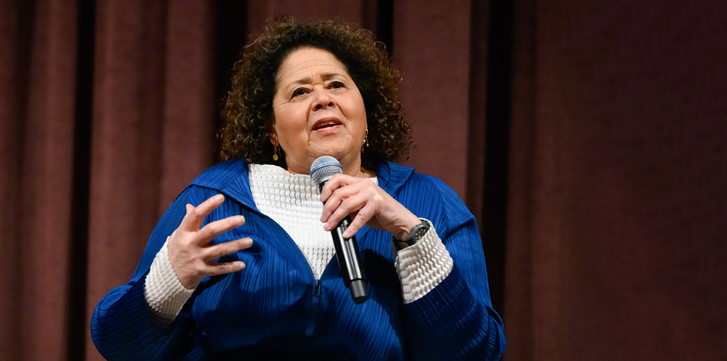 Woman speaking on stage with microphone in hand 