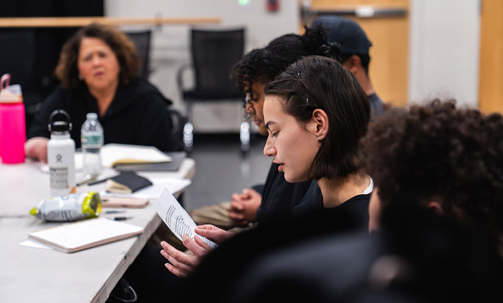 Students seated at table with artist