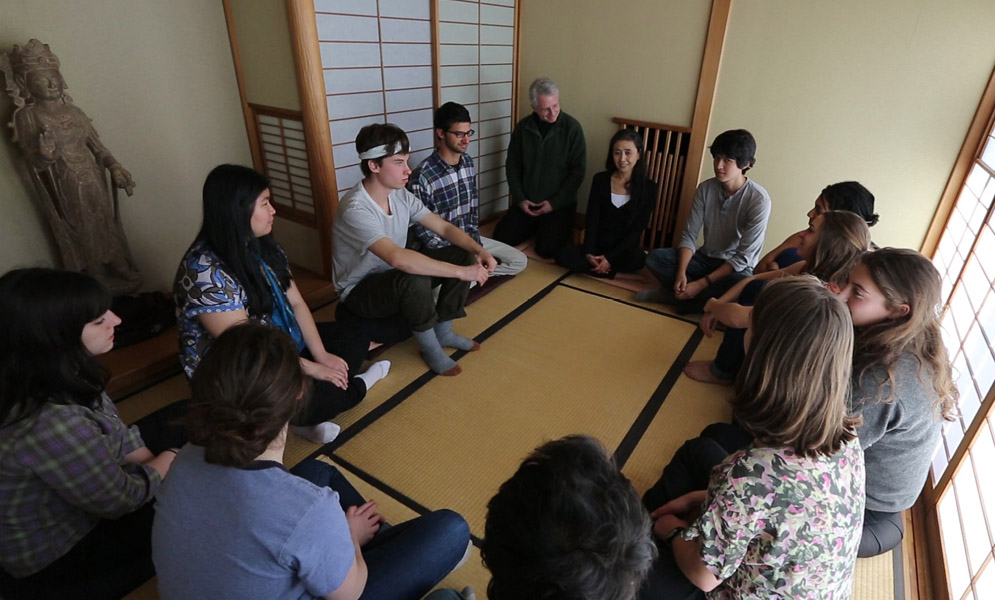 Artist speaking to group of students seated in circle on floor