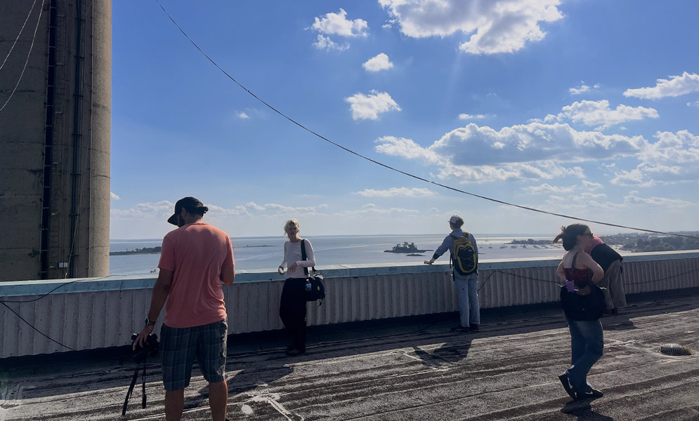 People walking on rooftop with clouds and ocean in the background