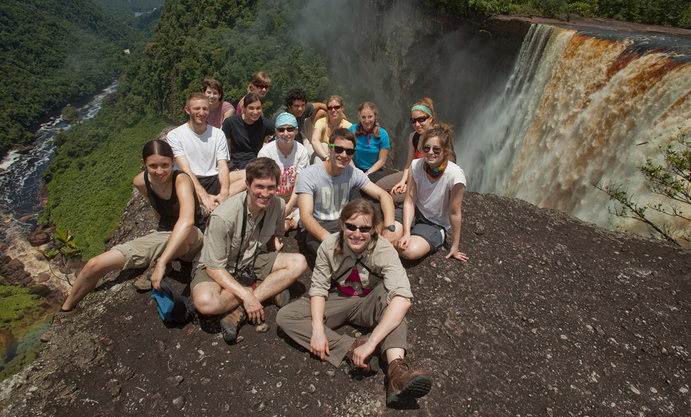 Students seated on ground by top of waterfall