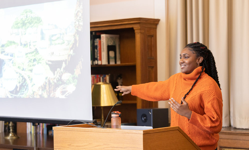 Student speaking at podium with slide projection
