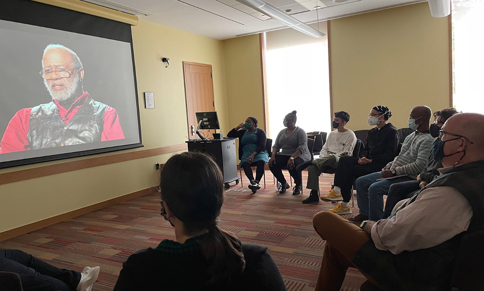 Group seated circle watching a video presentation on screen