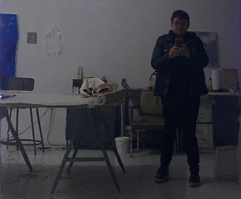 Reflection of artist in studio taking photo with phone