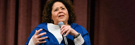 Woman speaking on stage with microphone in hand 