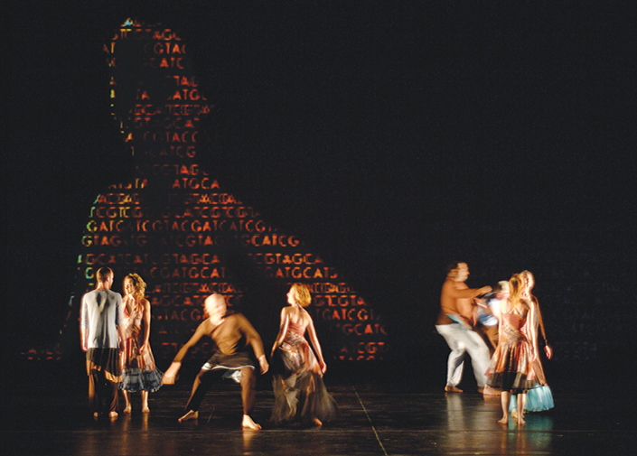 Dancers on stage with illustration of human genome projected in background