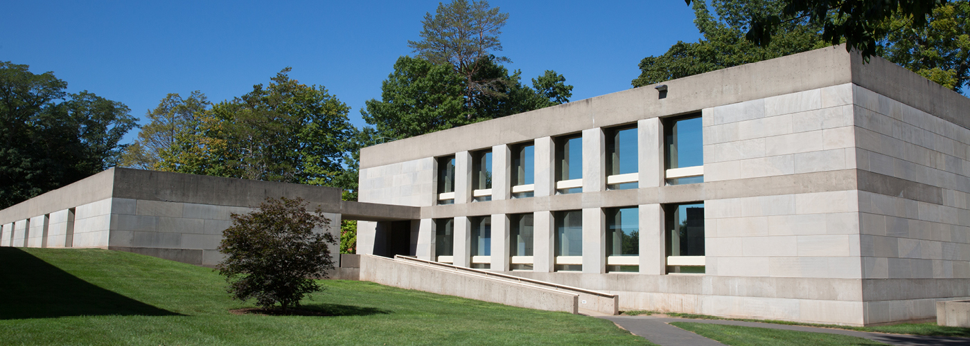 Limestone buildings with large windows with ramp and grass and trees in front 