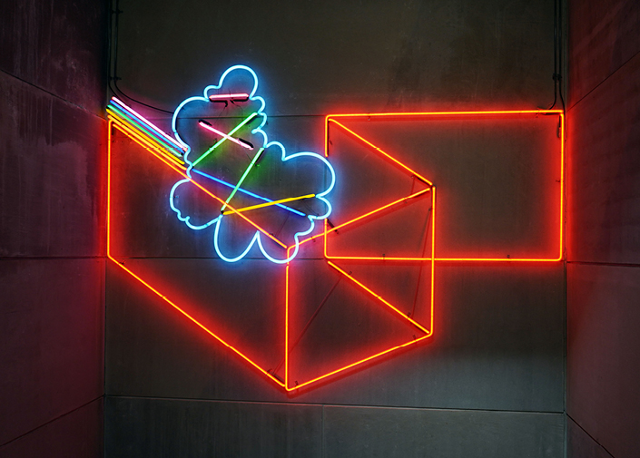 Orange, blue, green, and yellow neon light tubes on wall in organic and rectangular shapes