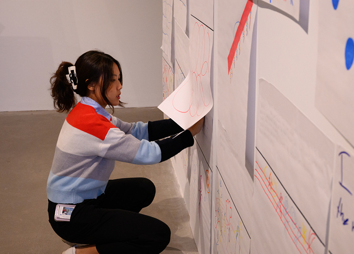 Two student curators standing in front of textile artwork on wall