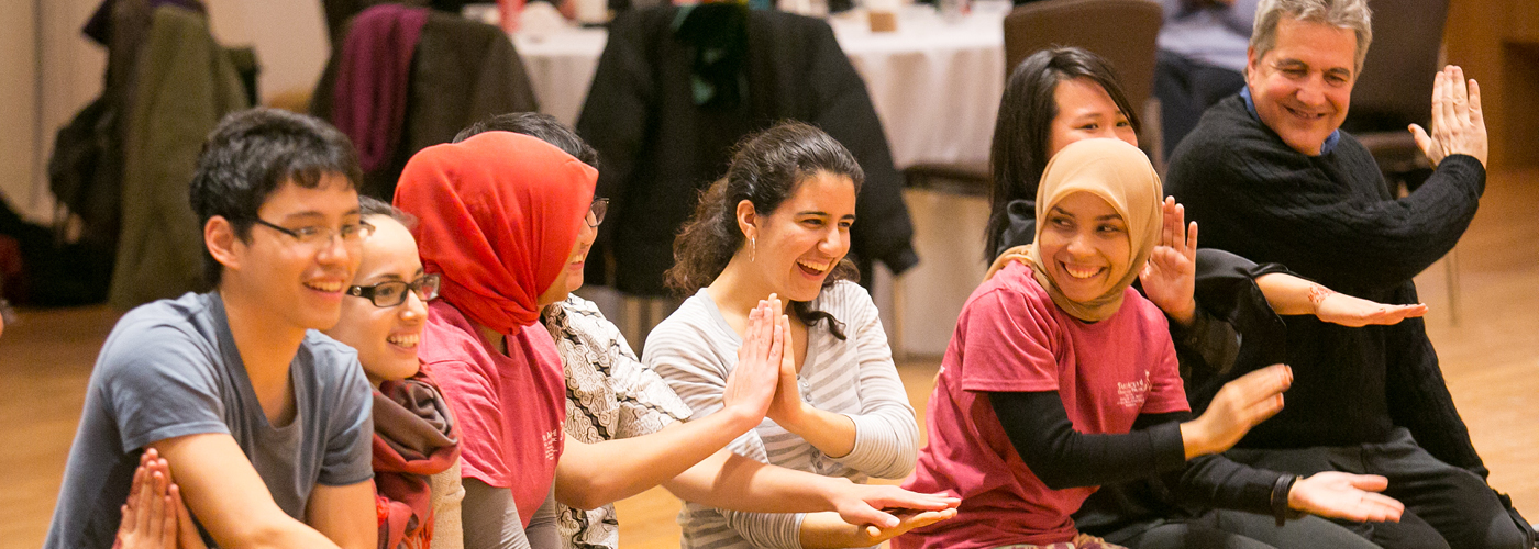 Dance workshop teachers and students seated on floor clapping hands