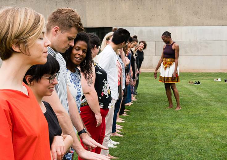 People lined up on field with dancer teaching in front