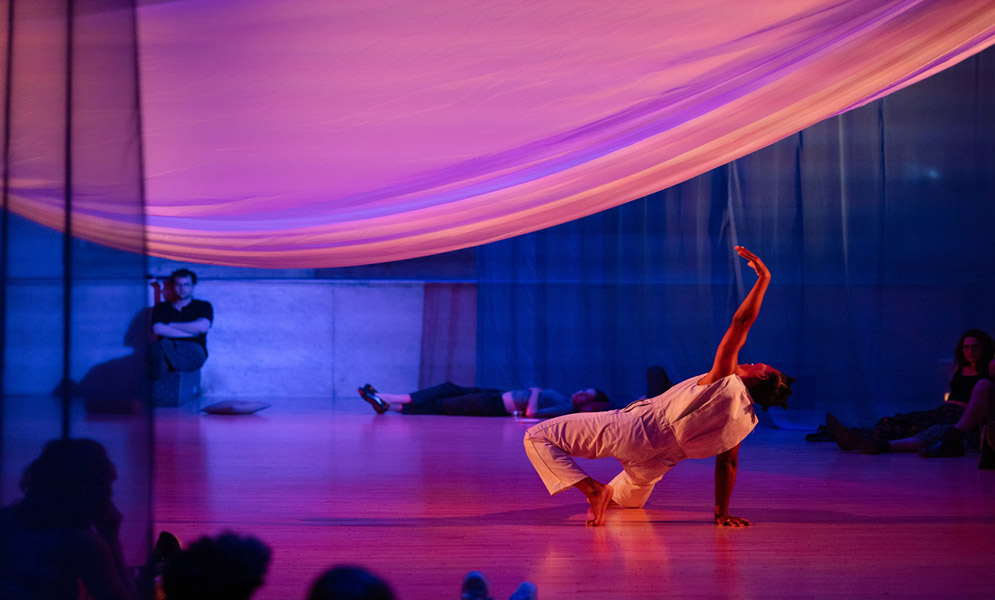 Person on floor reaching up to cloth above with others in background