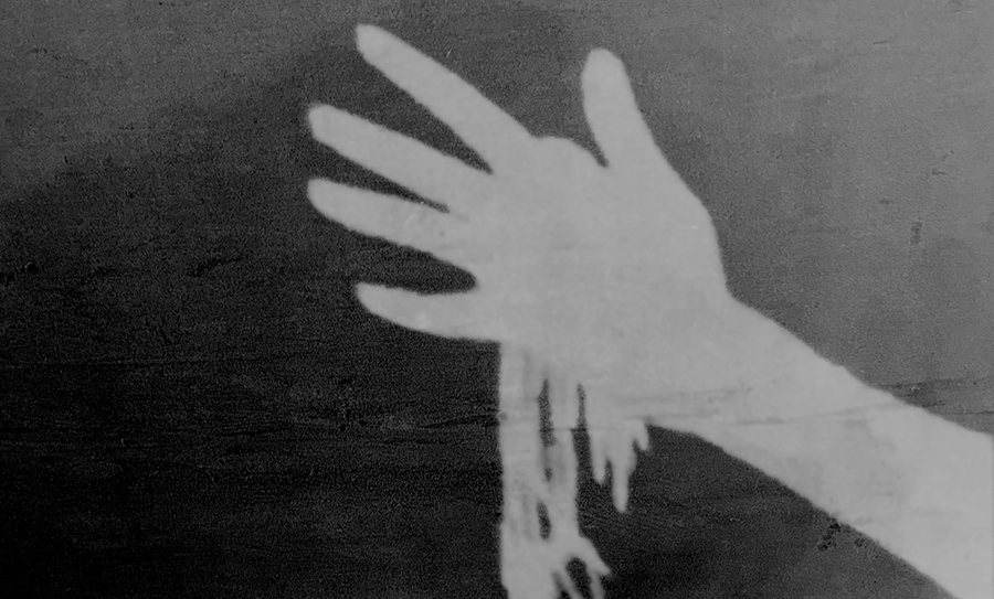 Inverted photo of hand with strands of material hanging down.