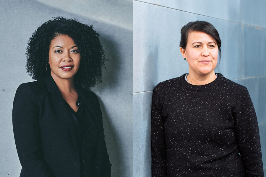 Two people dressed in black standing in front of gray walls.