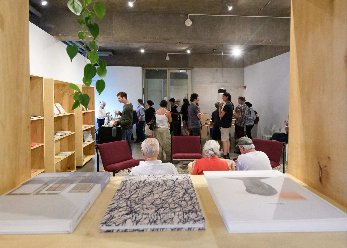 Interior of reading room with books displayed on shelves and people attending reception 