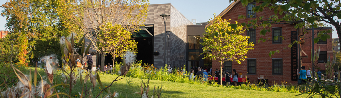 Arts building and people seen from distance with flowers and trees in foreground