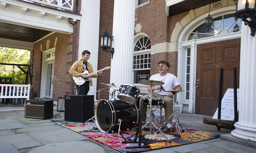Noah King '25 and Daniel Glickman '25, members of Goatherd, warm up on the patio of Alpha Delta Phi