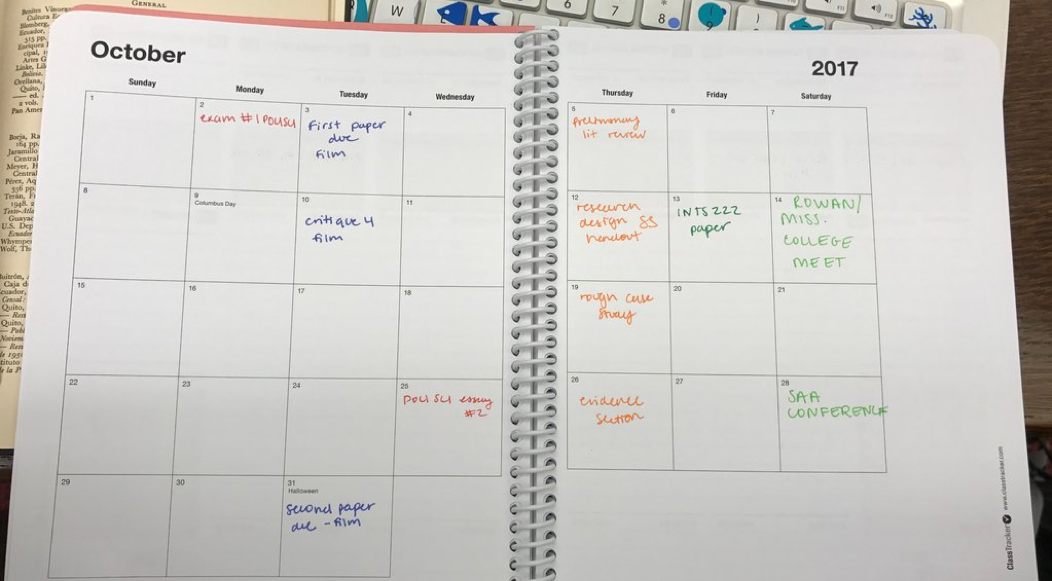 A month-view of a planner with assignments written in. Assignments are written in the calendar day they are due. Different color pens are used to identify the different classes.