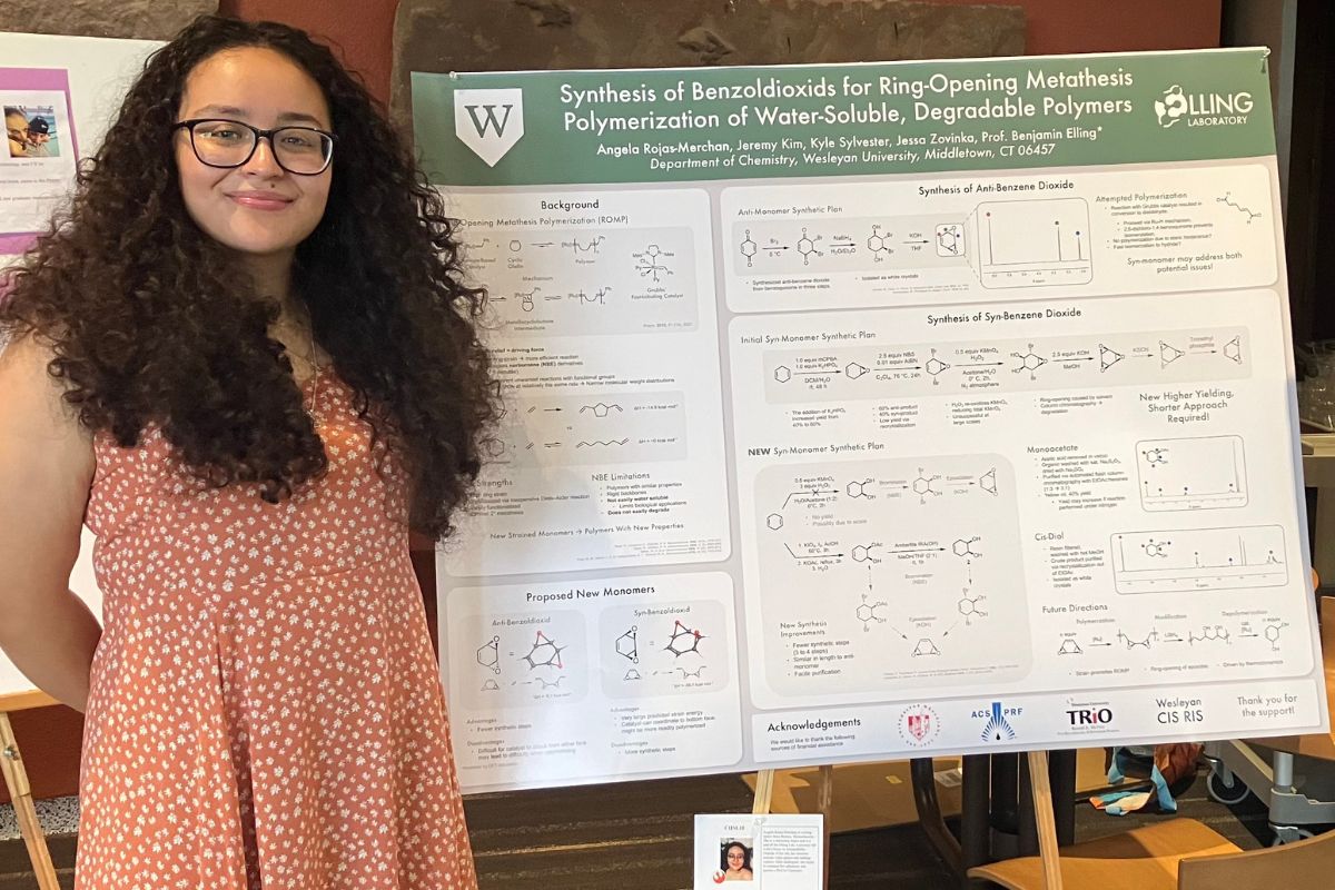 a young woman smiles in front of her scientific poster